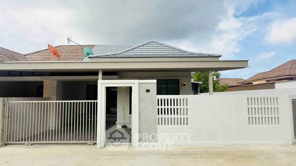 Modern single-story house with gated entrance and satellite dishes on the roof.