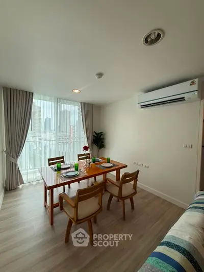 Modern dining area with city view, featuring elegant table setting and air conditioning.