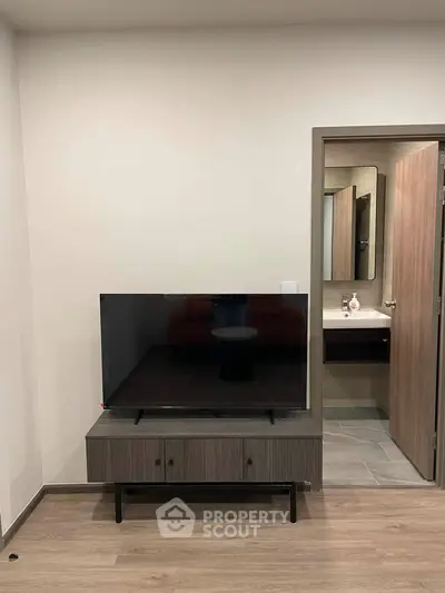 Modern living room with sleek TV stand and view into contemporary bathroom
