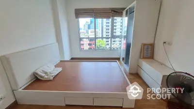 Spacious bedroom with city view, featuring a modern platform bed and large window for natural light.