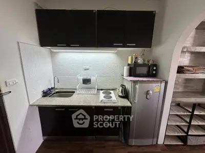 Compact kitchen with dark cabinets, granite countertop, and modern appliances
