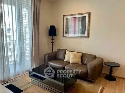 Modern living room with leather sofa, stylish decor, and natural light from large window.