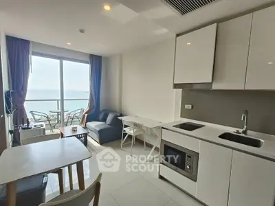 Modern open-layout living room with kitchen and ocean view balcony, perfect for relaxation and entertaining.