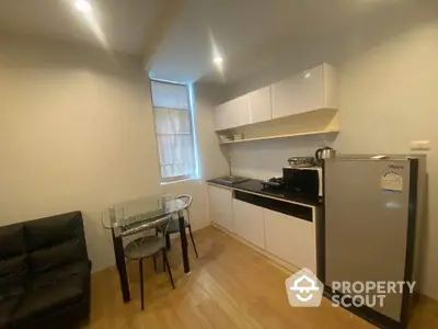 Modern kitchen with sleek cabinetry, compact dining area, and stainless steel appliances in cozy apartment.