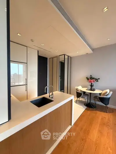 Modern kitchen with sleek design and cozy dining area, featuring elegant lighting and stylish decor.