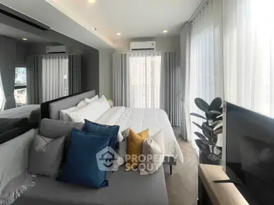 Modern bedroom with large windows, stylish decor, and a cozy seating area, perfect for urban living.