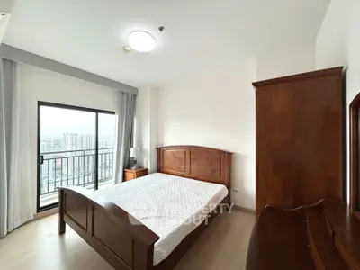 Spacious bedroom with wooden furniture and city view balcony in modern apartment.