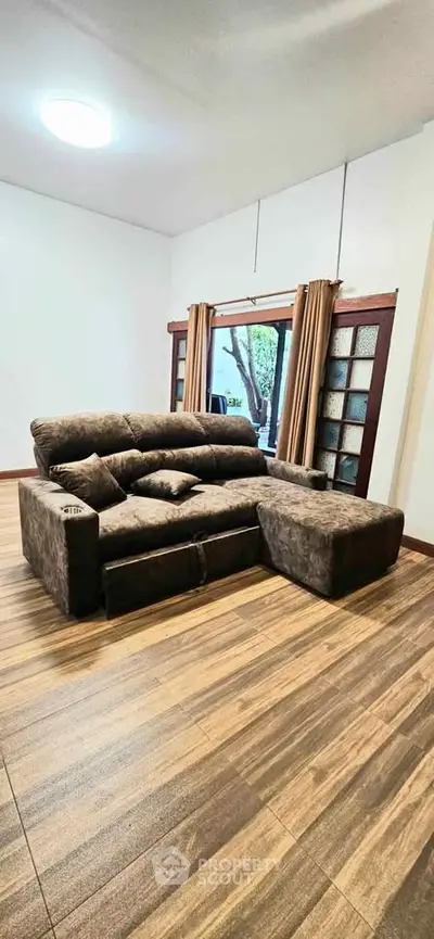 Spacious living room with cozy brown sectional sofa and large window view.