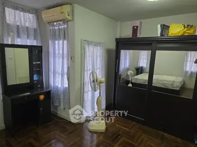 Cozy bedroom with wooden flooring, large wardrobe, and air conditioning unit