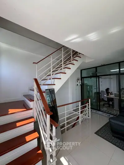 Modern interior with sleek staircase and glass-walled office space