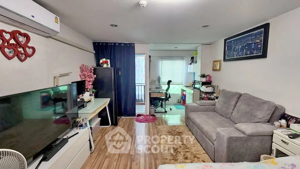Cozy living room with modern decor and city view, featuring a comfortable sofa and entertainment setup.
