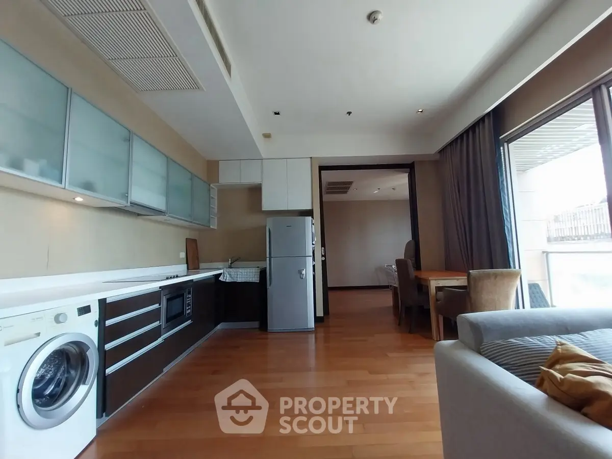 Spacious modern kitchen with open layout and dining area, featuring sleek appliances and wooden flooring.