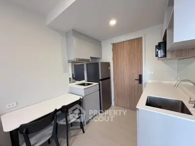 Modern compact kitchen with sleek design and dining area in a cozy apartment.