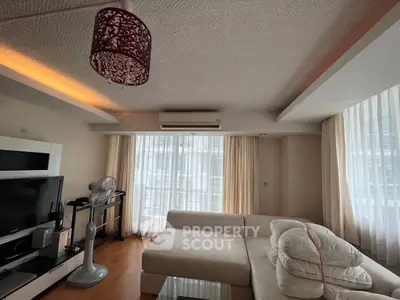Spacious living room with modern decor and natural light, featuring a cozy sectional sofa and entertainment setup.