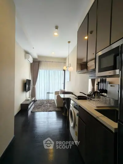 Modern apartment with sleek kitchen and cozy living area, featuring large windows and contemporary decor.