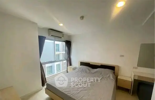 Spacious bedroom with large window and modern furnishings in a high-rise apartment.