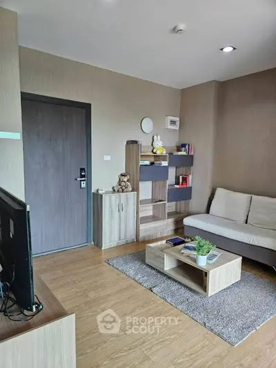 Modern living room with cozy sofa, wooden flooring, and stylish shelving unit.