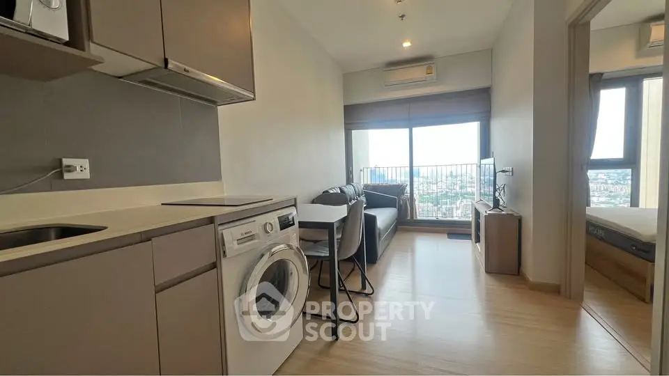 Modern apartment with open kitchen and living area, featuring a washing machine and city view.