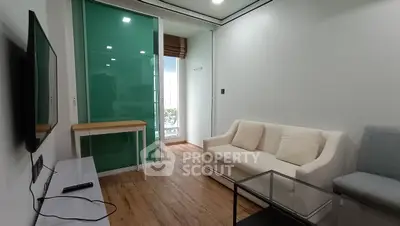 Modern living room with sleek furniture and glass door leading to balcony