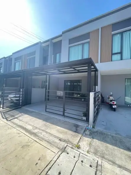 Modern townhouse exterior with carport and scooter parked in driveway.