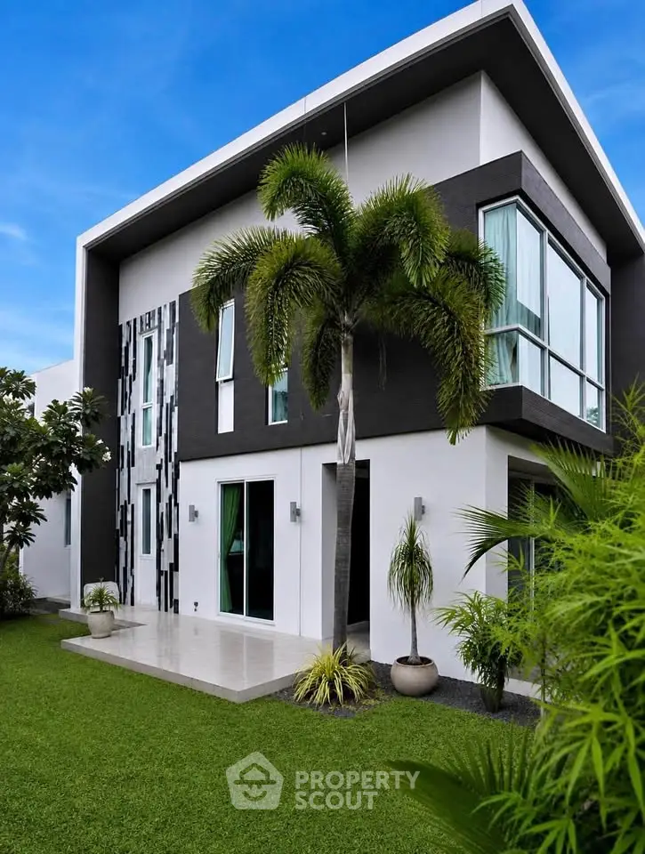 Modern two-story house with sleek design and lush green lawn, featuring large windows and contemporary architecture.