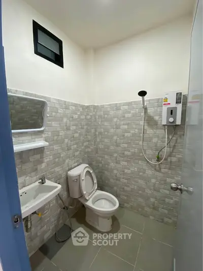 Modern bathroom with tiled walls, shower, and toilet in a real estate property.