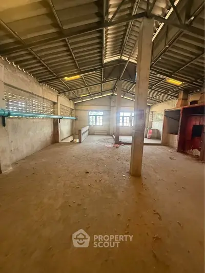 Spacious industrial warehouse interior with high ceilings and ample natural light.