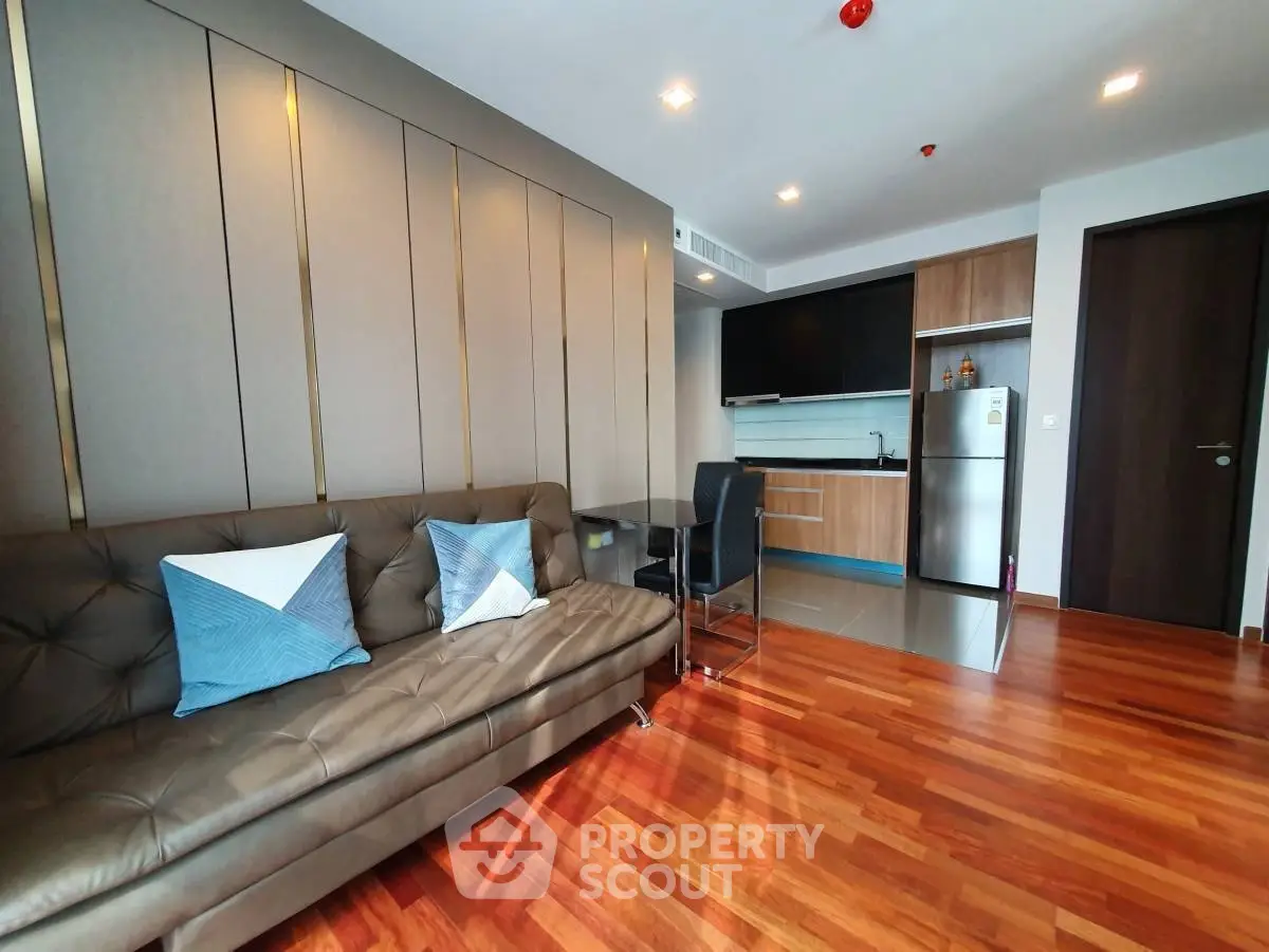 Modern living room with stylish decor and open kitchen layout, featuring hardwood floors and contemporary furniture.