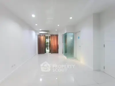 Spacious modern living room with white tiles and large windows for natural light.