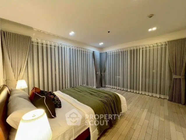 Spacious bedroom with elegant curtains and cozy lighting in modern apartment.