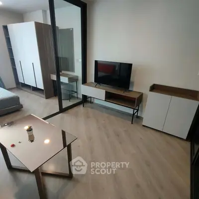 Modern living room with sleek furniture and glass partition, featuring a TV stand and stylish table.