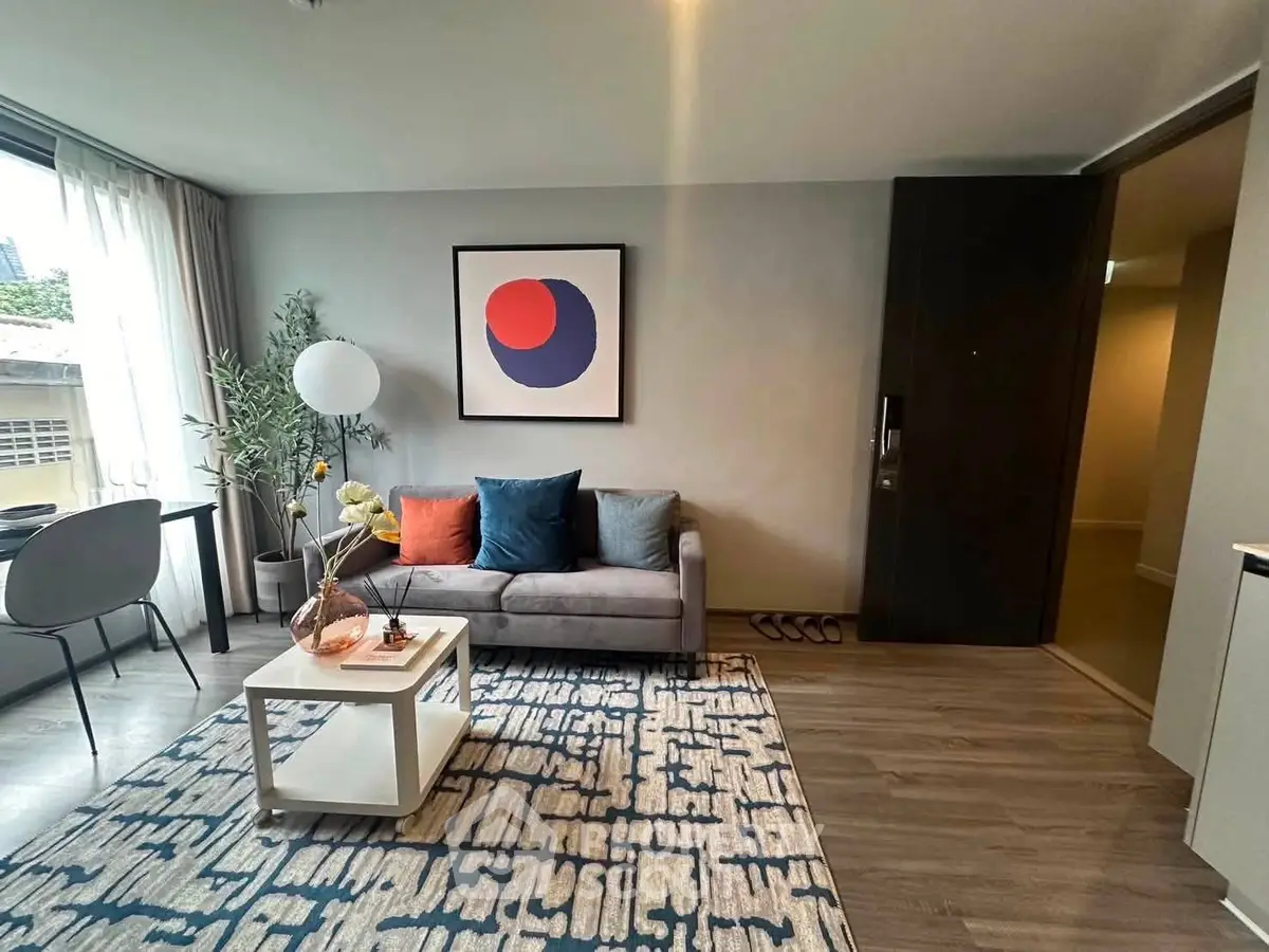 Modern living room with stylish decor and large window, featuring a cozy sofa and contemporary artwork.