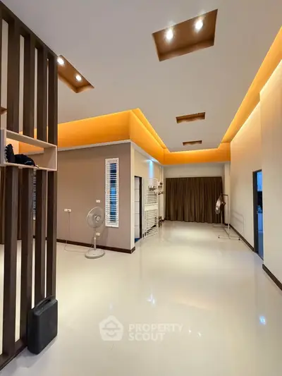 Spacious modern living room with stylish ceiling lights and sleek flooring, perfect for contemporary living.
