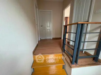 Charming interior hallway with wooden flooring and modern railing, leading to multiple rooms.