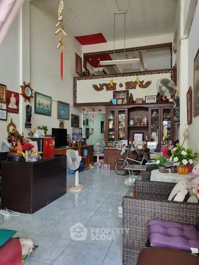Charming living room with high ceiling and eclectic decor, featuring a cozy seating area and unique cultural accents.