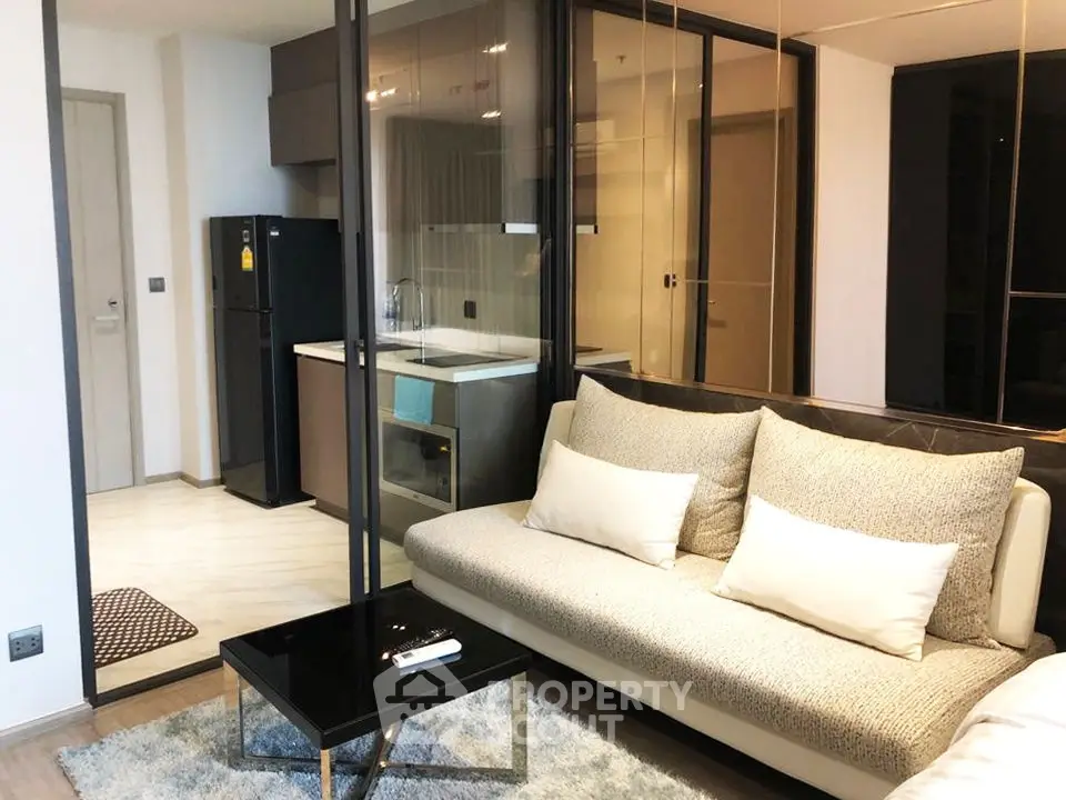 Modern living room with glass partition and sleek kitchen in a stylish apartment.