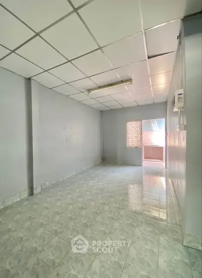 Spacious empty room with tiled flooring and natural light, ideal for customization.