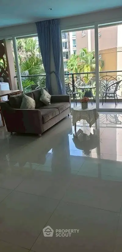 Spacious living room with large windows and balcony view, perfect for relaxation.