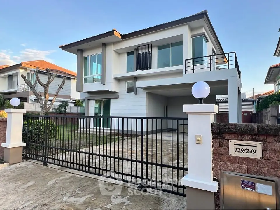 Modern two-story house with gated driveway and contemporary design.