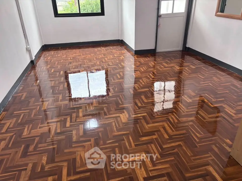 Stunning polished wooden floor in a bright room with large window and door, perfect for modern living.