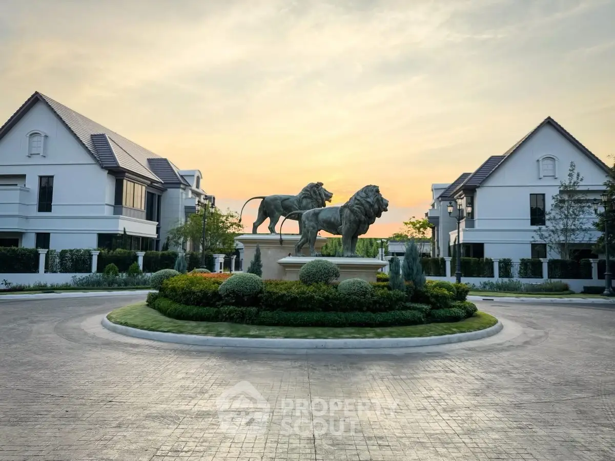Luxurious residential estate entrance with lion statues and elegant homes at sunset.