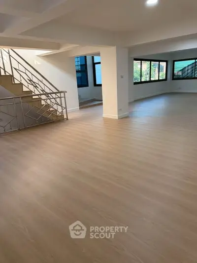 Spacious open-plan living area with modern staircase and large windows.