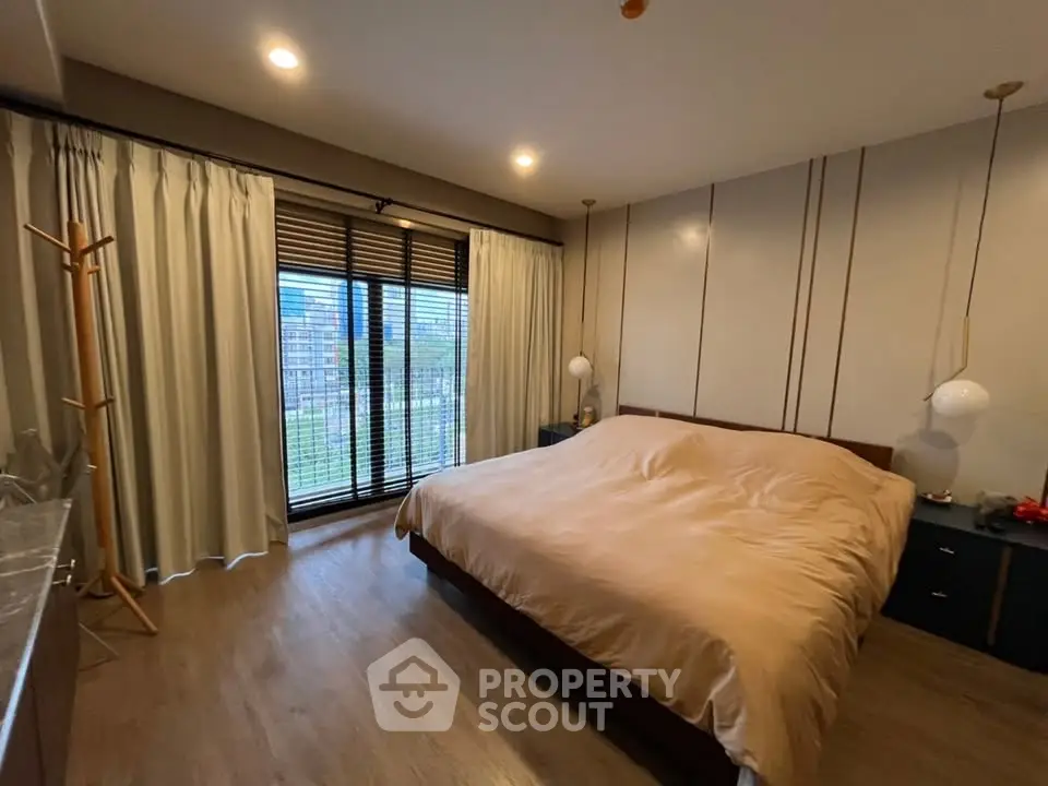 Spacious bedroom with large window and modern decor, offering a serene and comfortable living space.