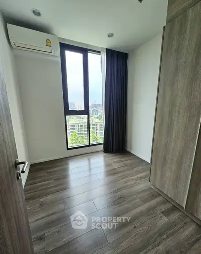 Bright bedroom with large window and wooden flooring in modern apartment