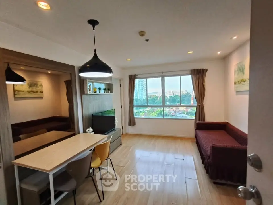 Spacious living room with modern decor and large window offering city views.