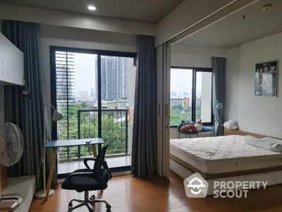 Modern bedroom with balcony and city view, featuring a cozy workspace and stylish decor.