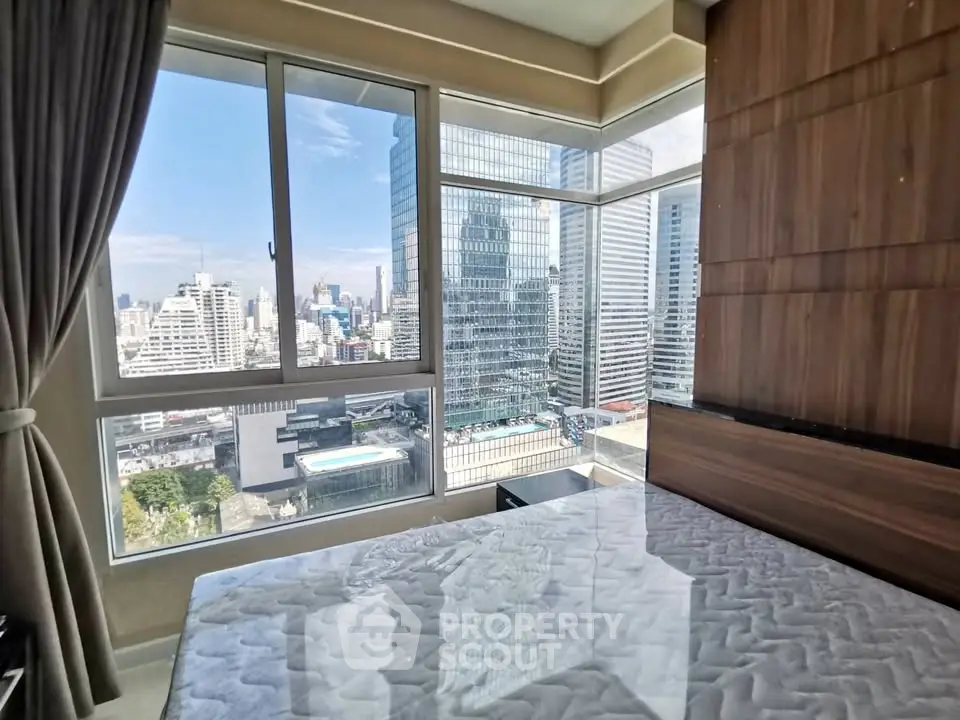 Modern bedroom with stunning city view and large windows in high-rise apartment.