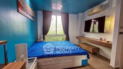 Modern bedroom with blue accents, featuring a wall-mounted TV and air conditioning.