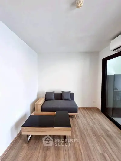 Modern minimalist living room with sleek sofa and stylish coffee table on wooden flooring.