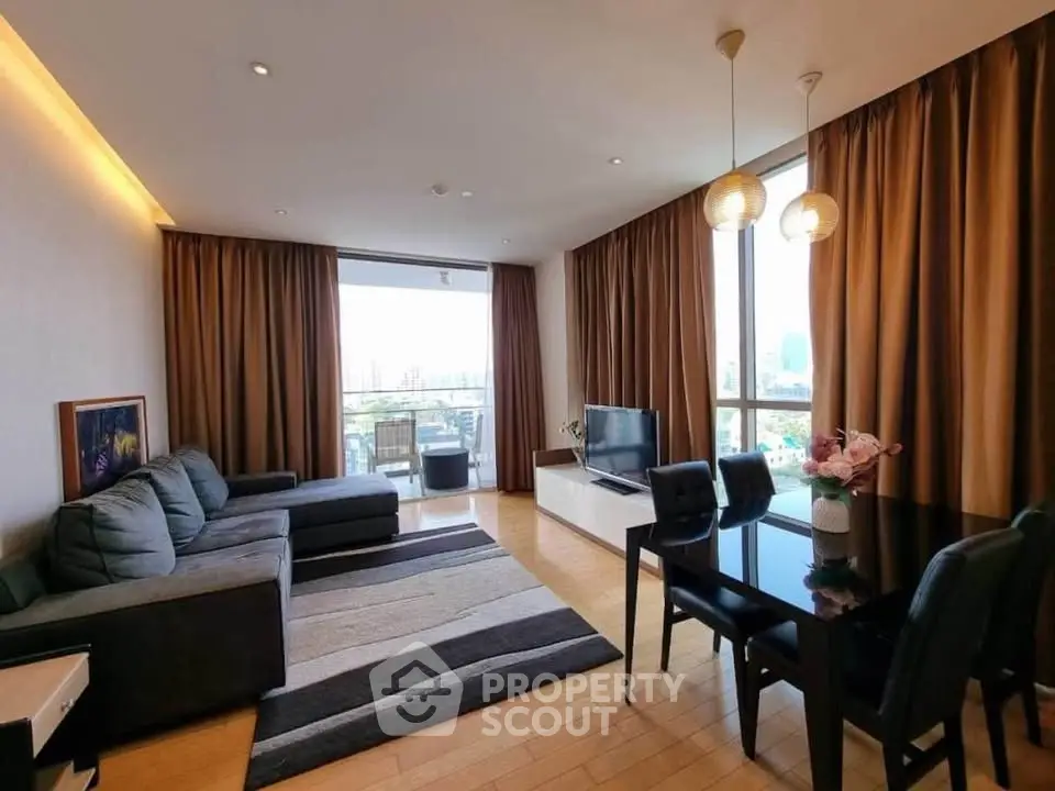 Spacious modern living room with large windows and city view, featuring elegant decor and cozy seating.